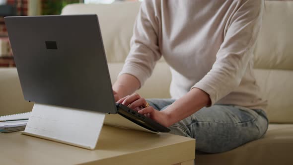 Excited Young Woman Sitting on Sofa at Home While Working Remotely on Laptop