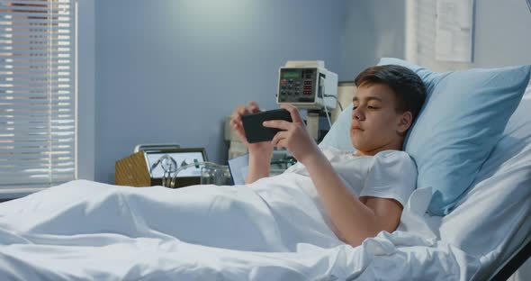 Teenager Patient Playing with Gameboy in Hospital