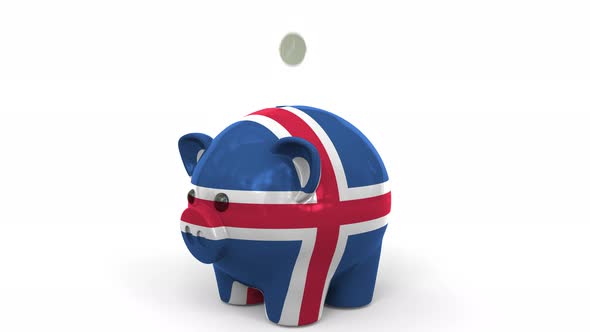 Coins Fall Into Piggy Bank Painted with Flag of Iceland alt