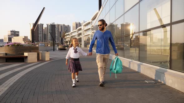 Father with Little Daughter in Uniform Going to School at Morning