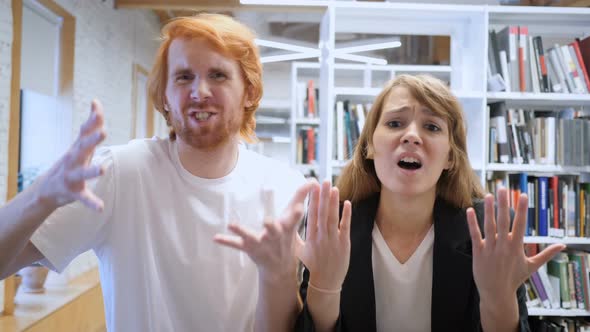 Young Man and Woman Reacting to Loss of Business in Office