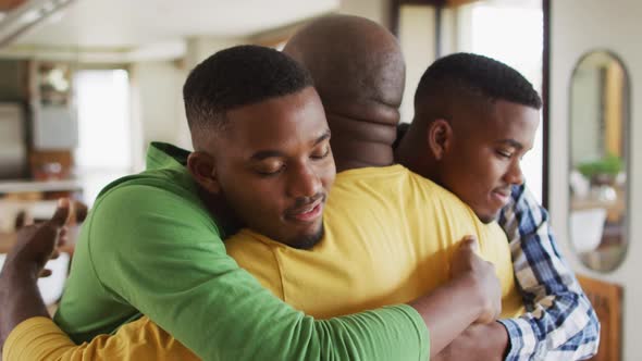 African american father embracing his twin teenage sons and smiling