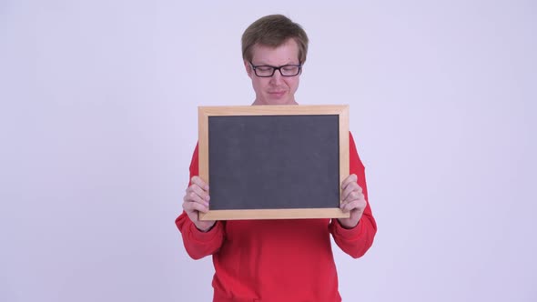 Stressed Young Man Revealing Face and Holding Blackboard