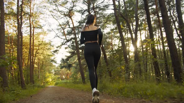 Young Woman Running in a Pine Forest