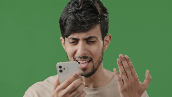 Stressed Arab Young Angry Guy Talk Smartphone Over Green Background Has Quarrel By Mobile Phone Bad