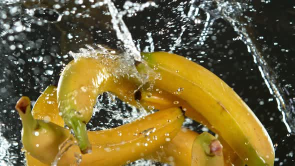 Super Slow Motion Shot of Flying Fresh Bananas and Water Side Splash Isolated on Black at 1000 Fps
