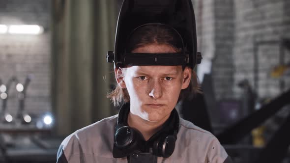 Young Man Working at the Construction Plant  Puts Down the Protective Helmet and Leans Down