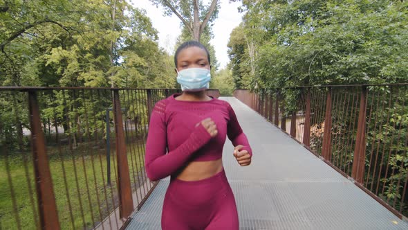 Black Woman Running on Bridge in Protective Medical Mask