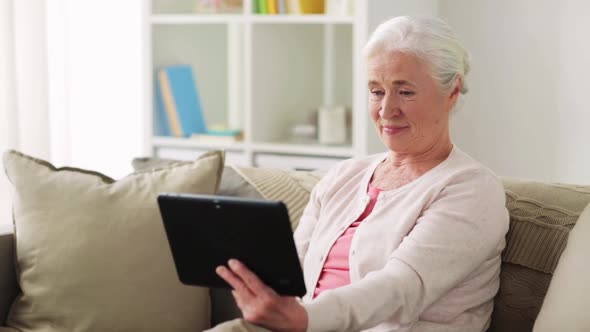 Old Woman with Tablet Pc Having Video Call at Home