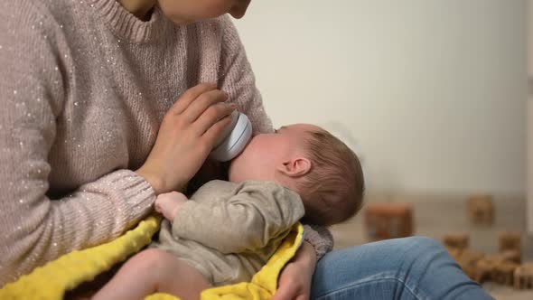 Babysitter Feeding Adorable Little Girl From Bottle, Anticolic Milk Formula