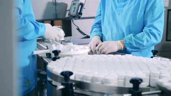 Factory Workers are Manually Closing Tubs with Pills