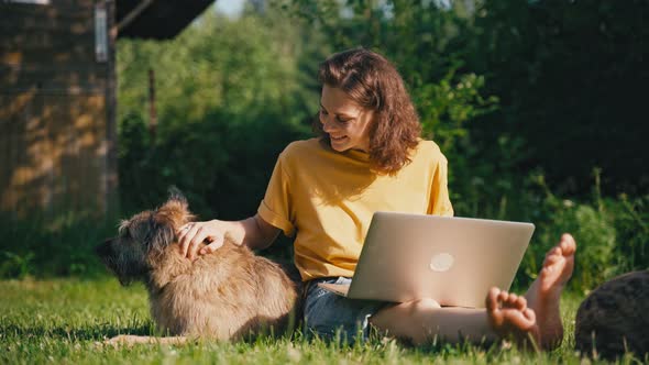 Young Woman Freelancer Works at a Laptop in the Countryside