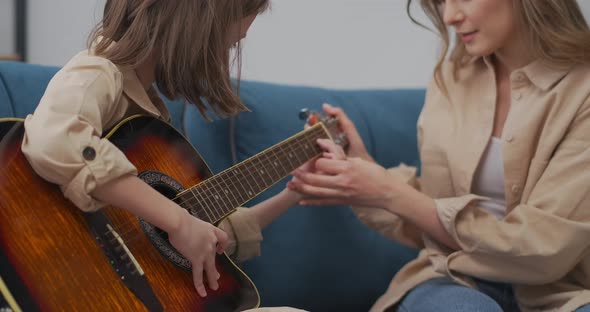 Mother and Daughter are Learning to Play Guitar Woman is Helping to Her Child Happy Family is
