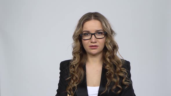 Female Disappointed Looks in Camera and Shrugs Then Waving His Head No Against Grey Background