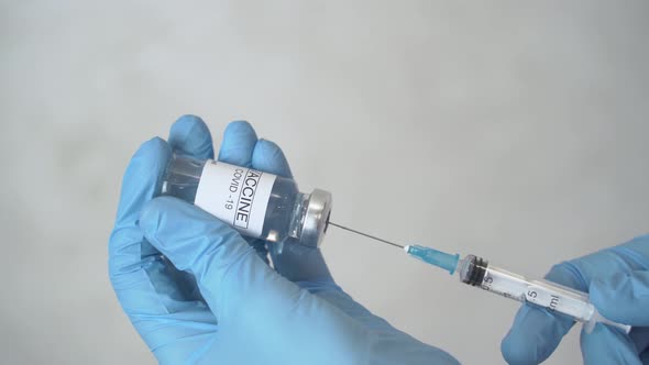 Doctor draws coronavirus vaccine into a syringe.