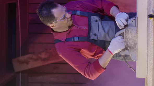 Vertical Shot Carpenter Cleans Surface of Wooden Beam with Electric Planer and Flies Sawdust