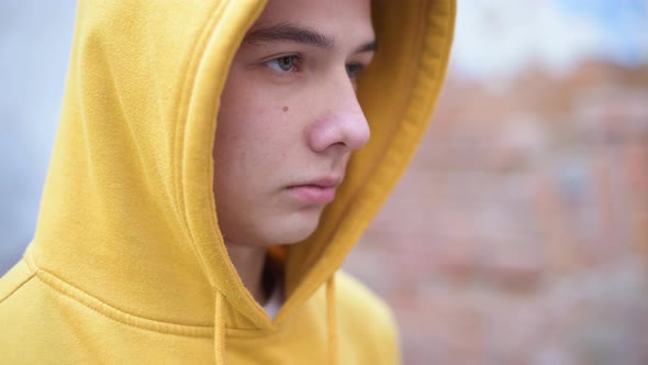 a teenager in a yellow sweatshirt looks in front of him
