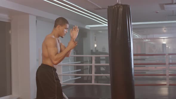 Selfimprovement Athletic Man Fighter Trains His Punches Beats a Punching Bag Training Day in the