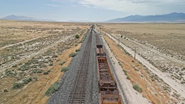 Flying over train tracks where cars are stopped before tracks merge