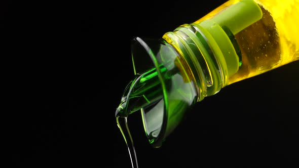 Slow motion shot of extra virgin olive oil being poured out a clear glass bottle