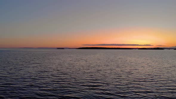 Drone flying calmly over water with sunset