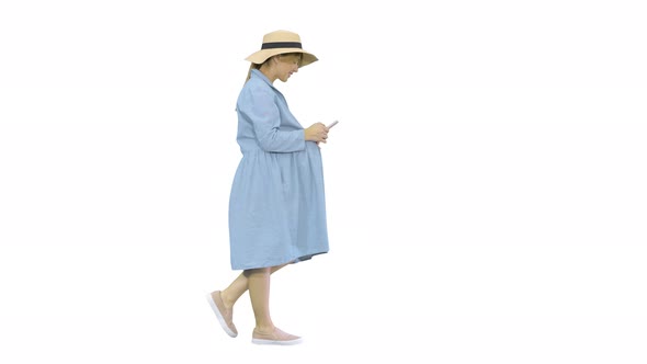 Young Pregnant Woman in Trendy Hat Walking and Using Her Phone on White Background