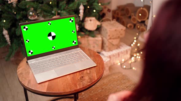 Woman in Christmas Communicates on Video Call Using Laptop with Green Screen