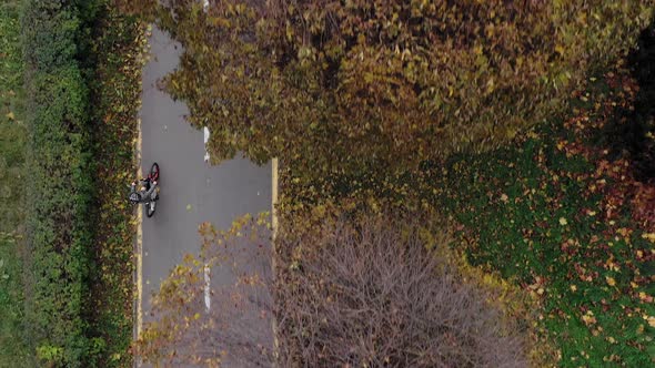 Aerial view Child riding bicycle in autumn park. Active sport family leisure