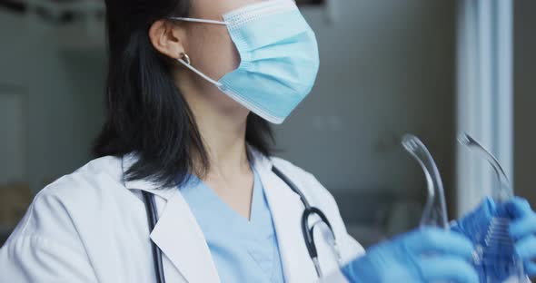 Asian female nurse wearing face mask putting on protective safety glasses in hospital