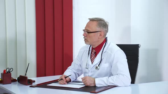 Male doctor speaks with patient in office. Physician at work.