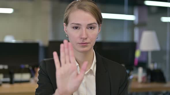 Portrait of Focused Young Businesswoman Doing Stop Sign with Hand