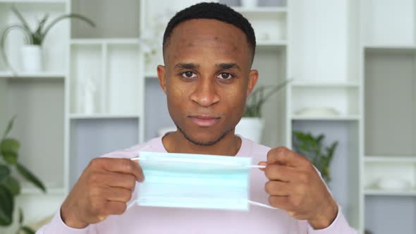 Portrait of African American Man Putting on Medical Mask Before Going Out As Protection Respirator