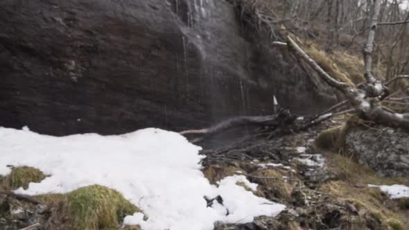 Water coming down onto snow and ice on a waterfall formed by melting snow_slowmo
