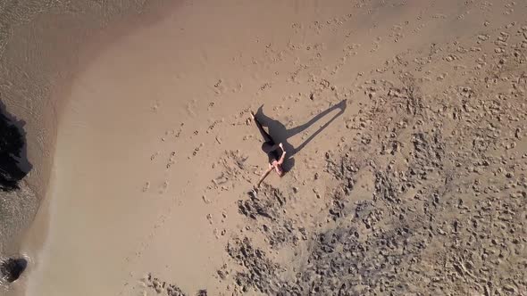 Sporty Girl in Tracksuit Stretches Legs on Sandy Beach