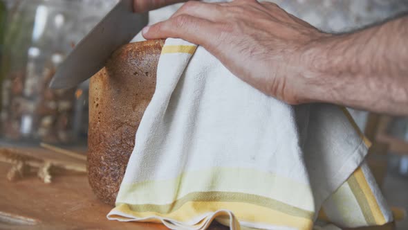A Male Hand Cuts a Crust From Fresh White Bread with a Toasted Crust on a Board and Covered with a