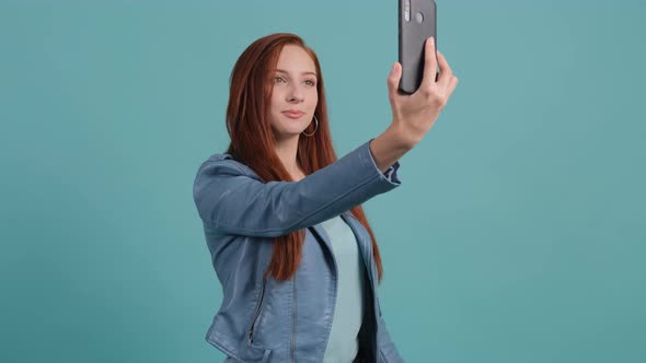 Funny Young Red Hared Woman Making Selfie on Turquoise Background