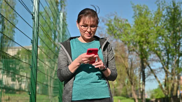 Active Mature Woman in Sportswear with Smartphone Outdoor