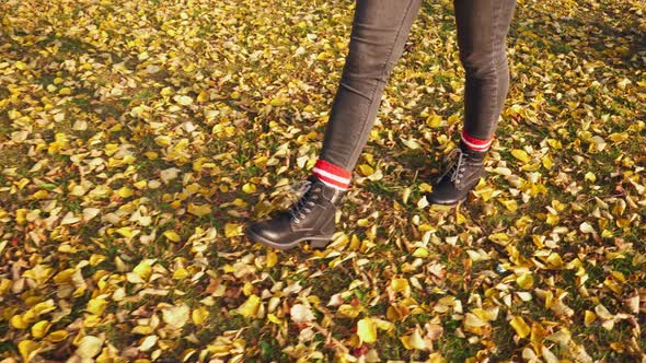 Feet in Black Boots Walk on Yellow Foliage