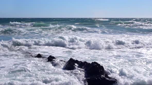 Rough sea waves splashing on the rocks and on the beach.