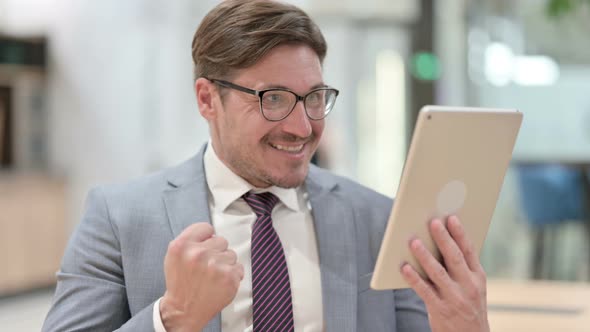 Portrait of Excited Businessman Celebrating Success on Tablet 