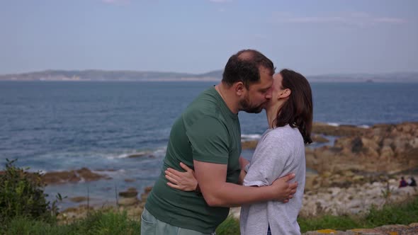 A Man and a Girl Couple Hug and Kiss Against the Backdrop of the Ocean