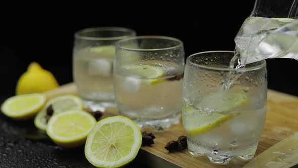 Pour Lemon Juice Into Glass with Ice and Lemon Slices. Lemon Alcoholic Cocktail