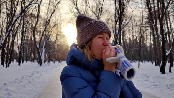 Woman in Blue Jacket and Hat Tries to Keep Warm Puts on Warm Knitted Mittens or Gloves with Pattern