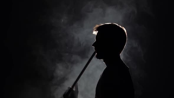 Profile View Silhouette Bearded Man Blowes Thick Smoke When Smoking Hookah on Black Background in