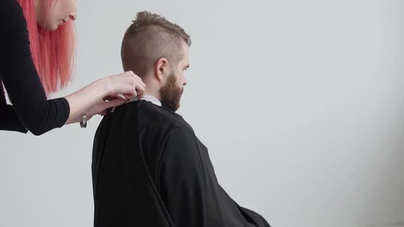 Young Red Haired Female Hairdresser Is Cutting Hair of Bearded Man Client