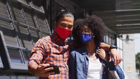 Diverse colleagues wearing face masks taking selfie using a smartphone