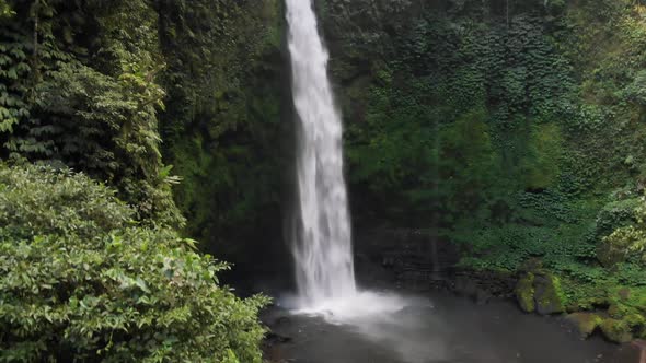 A drone captures the power and magnificence of the Nungnung Waterfall as it rises to the top of the