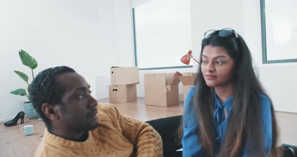 Young multi ethnic couple looking around in new home and into camera