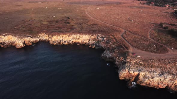 Drone top down aerial view of waves splash against rocky seashore, background. Flight over high clif