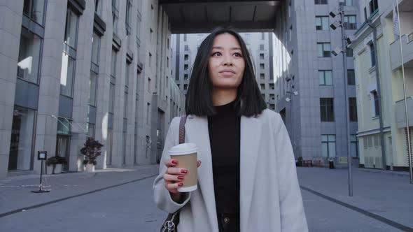 Young Adult Asian Businesswoman Walking From Office with a Coffee Cup in Slow Motion